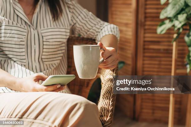 mockup image of woman's hands holding white mobile phone with blank screen on thigh and coffee cup in cafe - mug mockup stock pictures, royalty-free photos & images