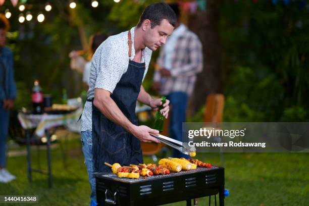 young man enjoying dinner party grill bbq  in garden yard - backyard grilling stock pictures, royalty-free photos & images