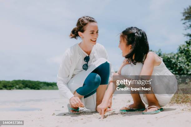 mother and young daughter playing on beach - eurasische herkunft stock-fotos und bilder