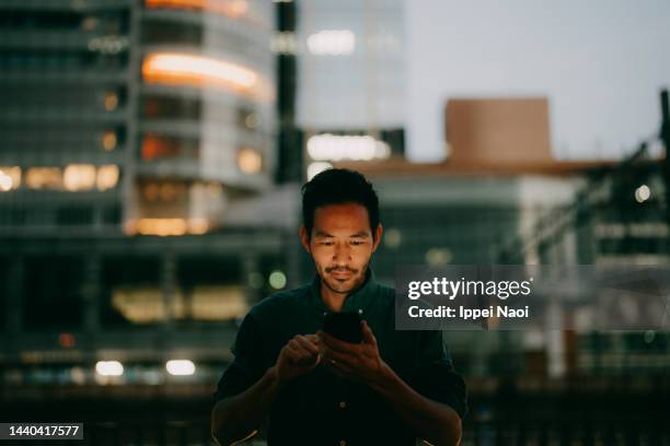 man using smartphone in city at night, tokyo - chiyoda stockfoto's en -beelden