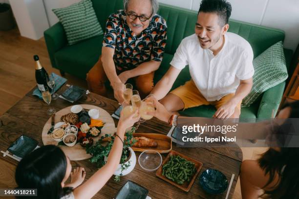 senior father and adult son toasting with family at home - asian family dinner stock pictures, royalty-free photos & images
