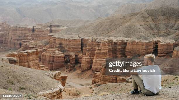 photo of a man enjoying the nature of the grand canyon. tourist on the background of the charyn canyon in kazakhstan - kazakhstan steppe stock pictures, royalty-free photos & images