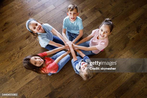 above view of happy kids uniting their hands on a floor. - children circle floor stock pictures, royalty-free photos & images