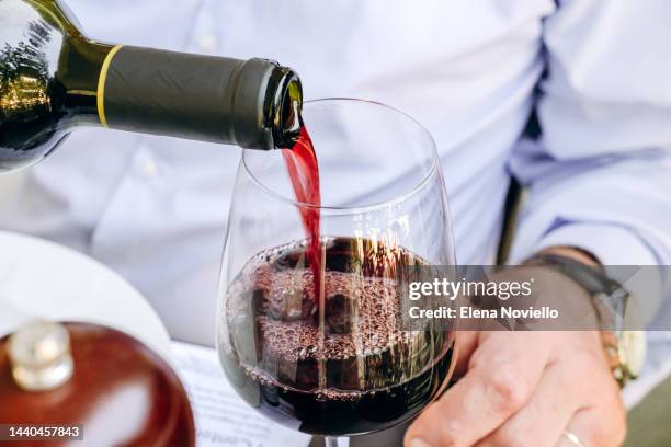 man pours red wine into glass - red wine foto e immagini stock