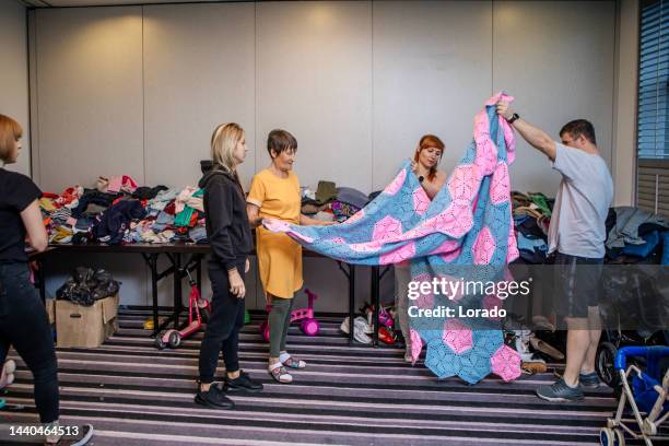 a cross generational group of refugees searching for clothes at a donation centre - ukrainian culture stock pictures, royalty-free photos & images