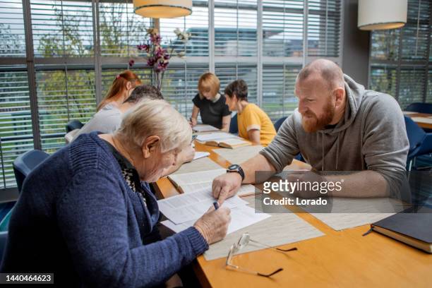a community care giver volunteering at a refugee learning centre - refugee aid stock pictures, royalty-free photos & images