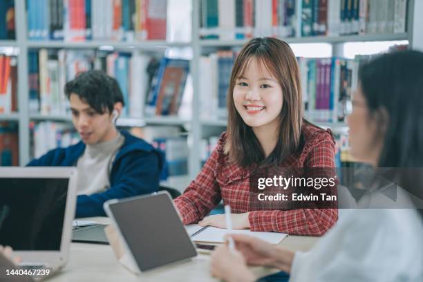 asiatisch-chinesische studentin schaut während der lerngruppe in der bibliothek lächelnd in die kamera - chinese tutor study stock-fotos und bilder