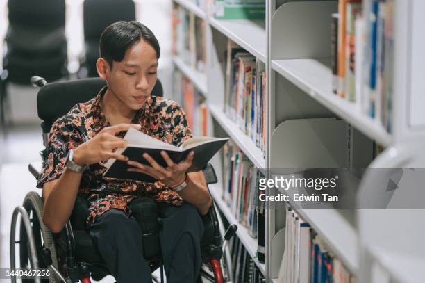 asiatischer teenager mit behinderung im rollstuhlleser buch in der bibliothek - boy reading a book stock-fotos und bilder