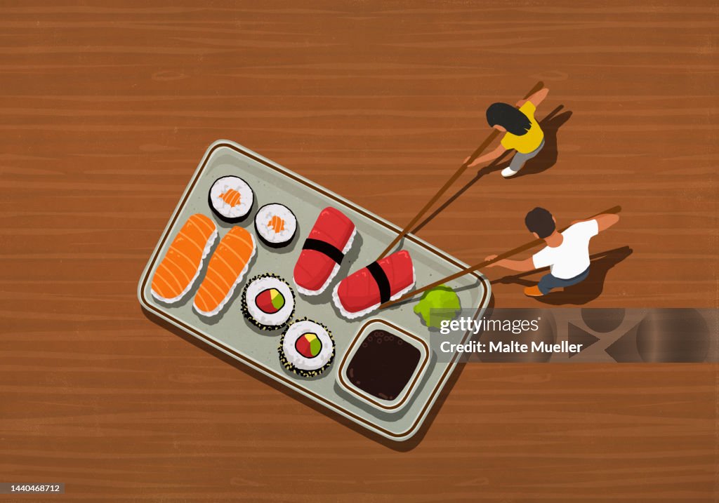 Couple with chopsticks eating large tray of sushi