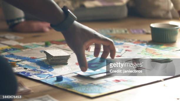 african ethnicity human hand picking up game card on a game board. diverse family game night - boardgame stockfoto's en -beelden