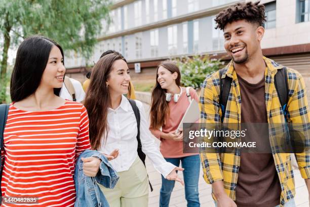 multiracial group of young college students walking outside on campus while talking and having a good time. - school fair stock pictures, royalty-free photos & images