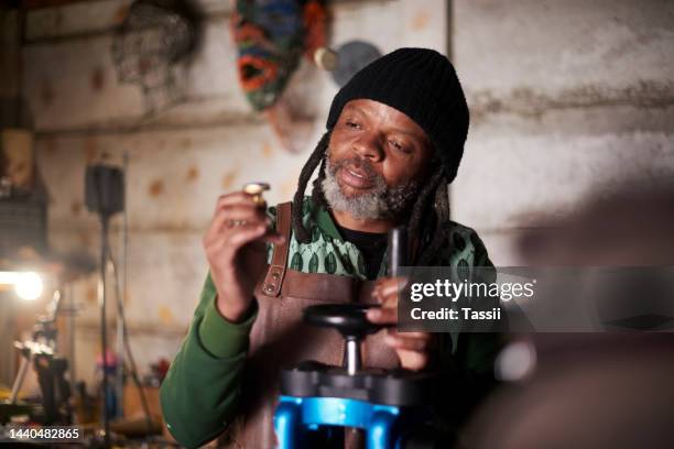 black man in workshop, jewelry designer manufacturing handmade silver ring in nigeria. traditional goldsmith tools, creative woodwork industry in warehouse studio and artist holding steel product - metal fingers stock pictures, royalty-free photos & images