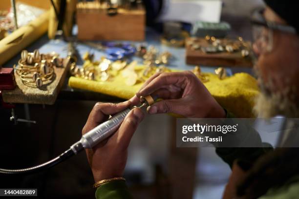 jeweler, black man and metal worker working on jewelry for a hobby or profession in a garage. construction tool, handy work and employee craft to make a ring from gold in a warehouse or factory - jeweller tools stock pictures, royalty-free photos & images