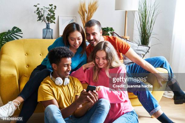 multiracial group of friends sitting in modern city apartment buying concert tickets by mobile phone. - concert ticket stock pictures, royalty-free photos & images