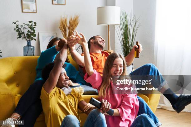 friends in living room at home watching awards ceremony on tv, celebrating their favorite singing group winning. - awards winners room stock pictures, royalty-free photos & images