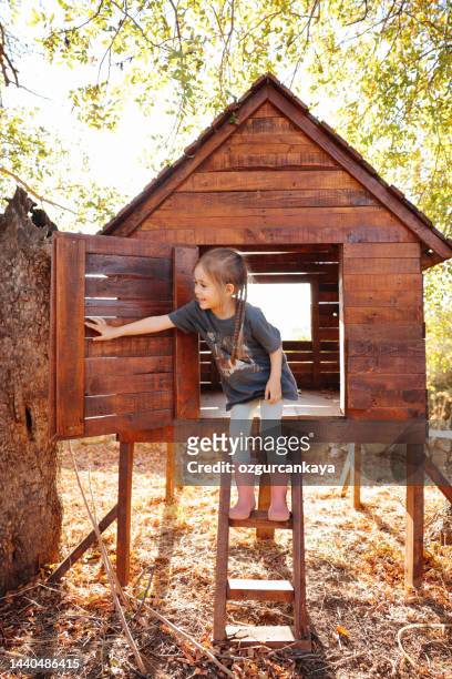 girl plays in creative handmade treehouse in backyard, summer activity, happy childhood, cottagecore - casa de brinquedo imagens e fotografias de stock