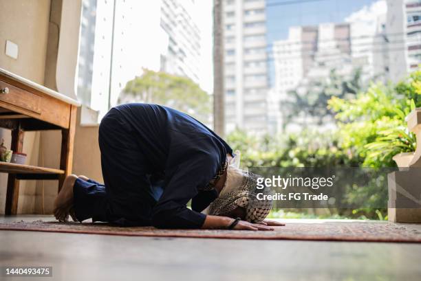 junge muslimische mann beten - prayer mat stock-fotos und bilder