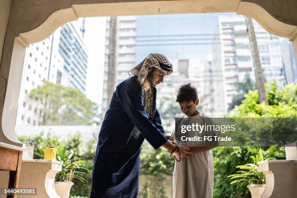 young man teaching younger brother to pray - kaffiyeh stock pictures, royalty-free photos & images
