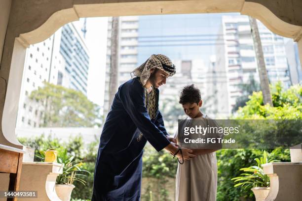 young man teaching younger brother to pray - kaffiyeh bildbanksfoton och bilder
