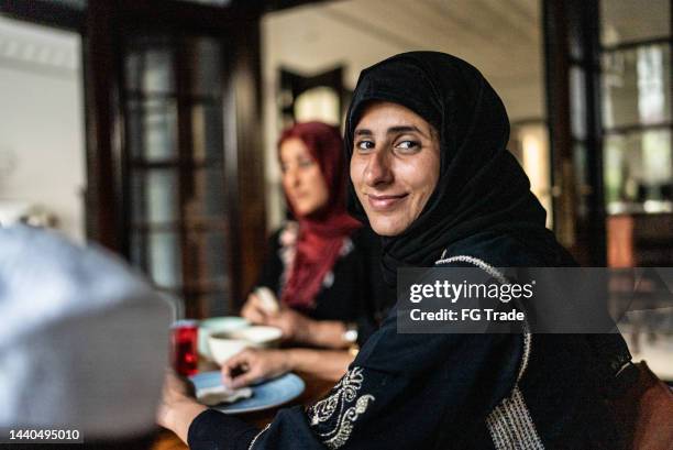 porträt einer mittelerwachsenen frau, die mit der familie zu hause zu mittag isst - lebanese food stock-fotos und bilder