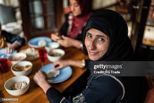 portrait of a mid adult woman having lunch with family at home - lebanese ethnicity stock pictures, royalty-free photos & images