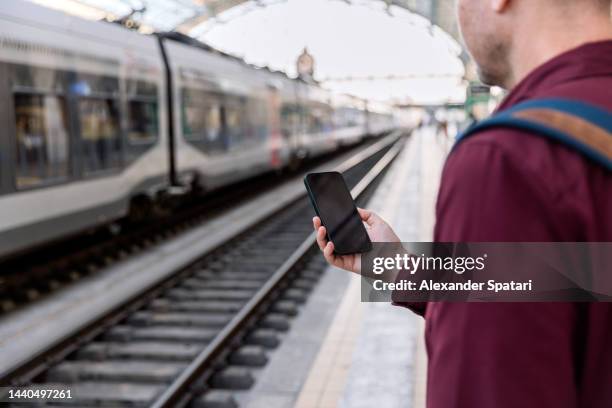 man using smartphone on a train station platform, rear view - plataforma de estação de metro imagens e fotografias de stock