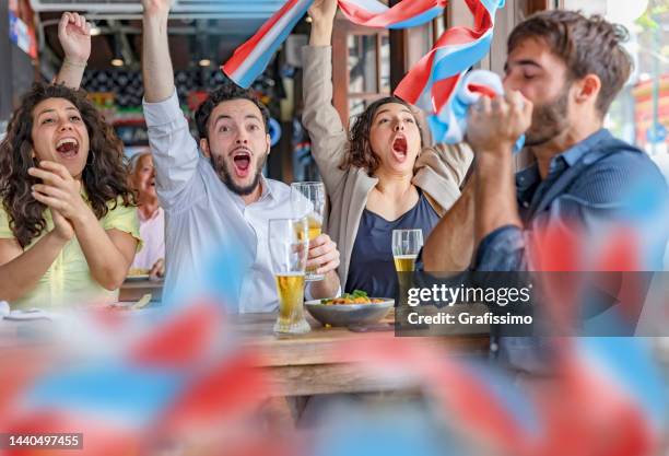 group of soccer fans friends celebrating goal in pub with national flag - public viewing stock pictures, royalty-free photos & images