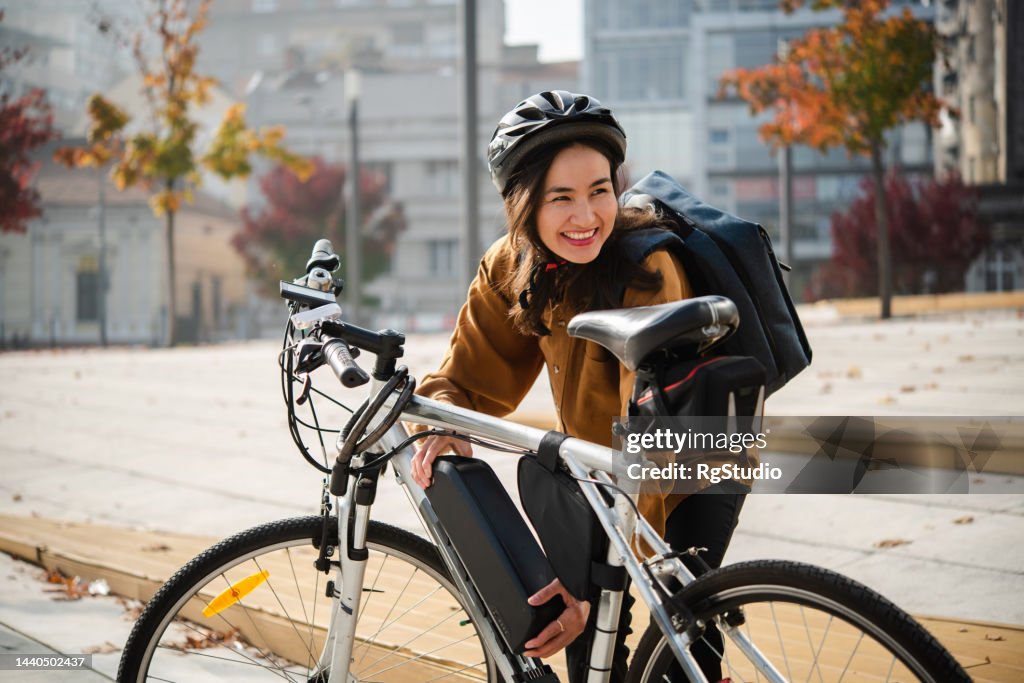 Asiatische Geschäftsfrau bereitet ihr E-Bike darauf vor, daran zu arbeiten