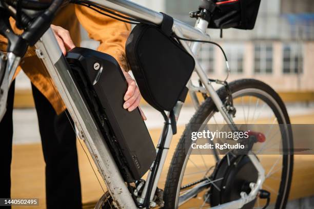 unrecognizable woman changing battery on her electric bicycle - ebike stock pictures, royalty-free photos & images