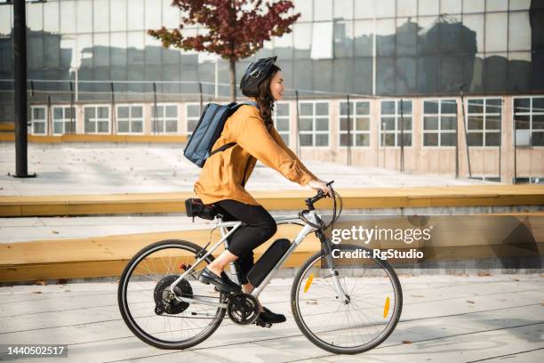 asian businesswoman cycling through the city - e bike stock pictures, royalty-free photos & images