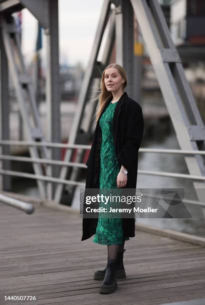 Lil Paulin seen wearing a green patterned long dress, a black long coat and black and dark green leather boots by Copenhagen Studios on November 08,...