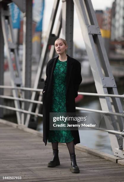 Lil Paulin seen wearing a green patterned long dress, a black long coat and black and dark green leather boots by Copenhagen Studios on November 08,...