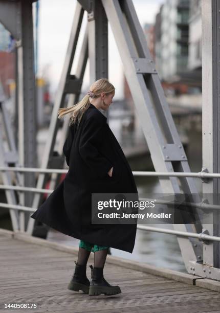 Lil Paulin seen wearing a green patterned long dress, a black long coat and black and dark green leather boots by Copenhagen Studios on November 08,...