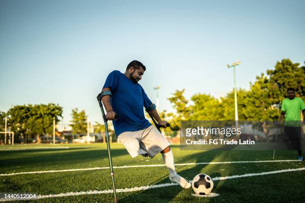 mid adult amputee player hitting penalty kick on soccer field - straff sportaktivitet bildbanksfoton och bilder