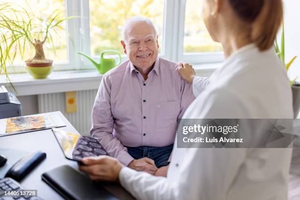 senior male patient being advised by surgeon in clinic - neurologist stock pictures, royalty-free photos & images