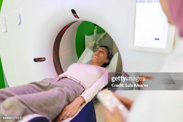 woman patient undergoing mri scan in examination room - radioterapia fotografías e imágenes de stock
