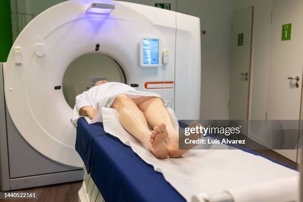 senior man wearing hospital gown undergoing ct scan - radiotherapy stock pictures, royalty-free photos & images