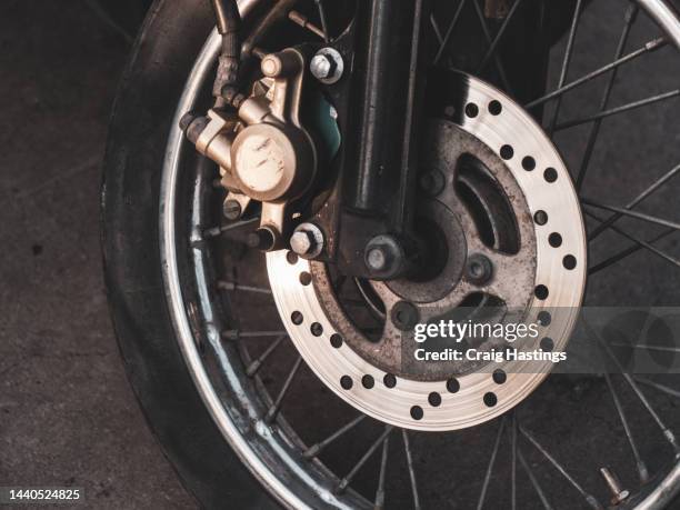 extreme close up of motorbike front wheel brake disc in warm golden colours with copy space. - motorcycle wheel stock pictures, royalty-free photos & images