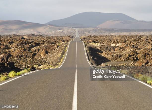 road leading into the distance in volcanic landscape - vía principal fotografías e imágenes de stock