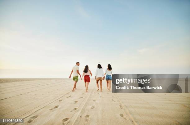 wide shot of family walking on empty beach at sunrise during vacation - 40 49 years stock pictures, royalty-free photos & images