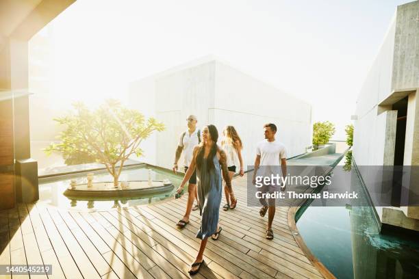wide shot of family walking though grounds of luxury tropical resort - family holidays hotel stock pictures, royalty-free photos & images