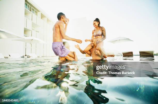 wide shot of smiling family playing in pool at tropical resort - holiday resort family sunshine stock pictures, royalty-free photos & images