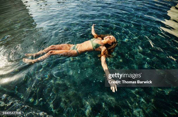 wide shot of girl floating on back in pool at tropical resort - mexican independence day stock pictures, royalty-free photos & images