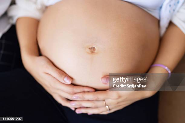femme enceinte de race blanche méconnaissable touchant son ventre - femme main ventre photos et images de collection