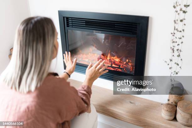 woman heating the house. concept of energy crisis - foyer de cheminée photos et images de collection