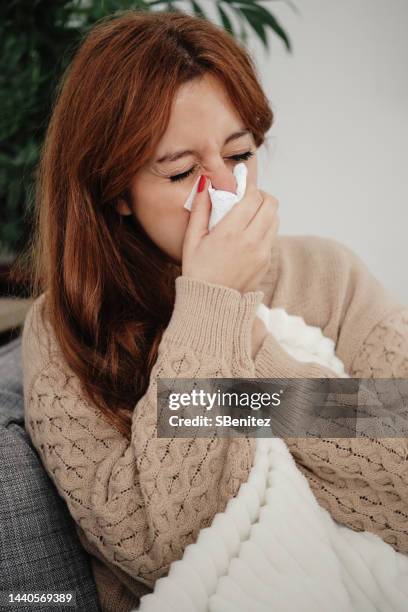 woman with the flu blowing her nose - sonarse fotografías e imágenes de stock