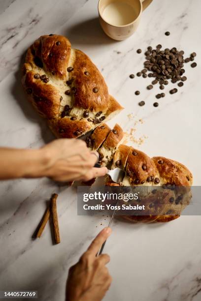 two hands cutting several slices of chocolate braided bread - geflochtenes brot stock-fotos und bilder