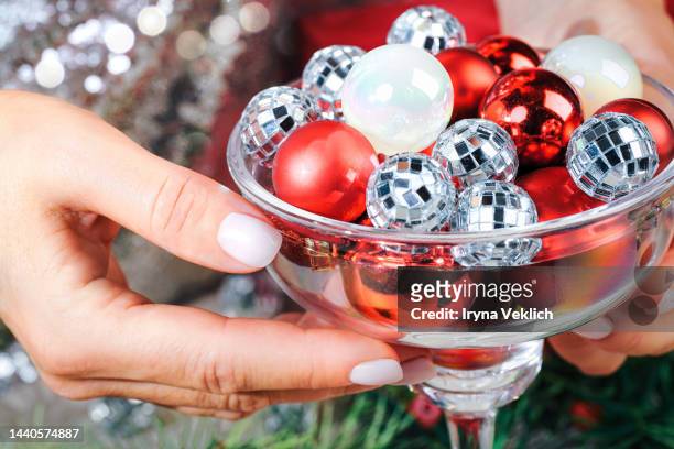 xmas present, gift, congratulation, new year party invitation.  winter holidays and black friday concept with woman's hand and disco balls in cocktail glass. - adult cocktail party background stock-fotos und bilder