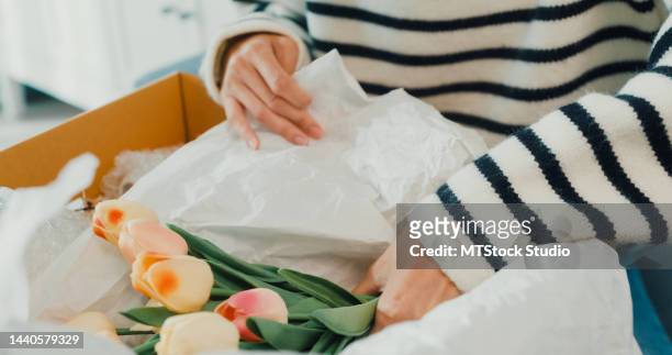 close-up excited young asian girl wear sweater opening unbox cardboard box vase decoration home from furniture shop with happy moment on sofa couch. - receiving flowers stock pictures, royalty-free photos & images