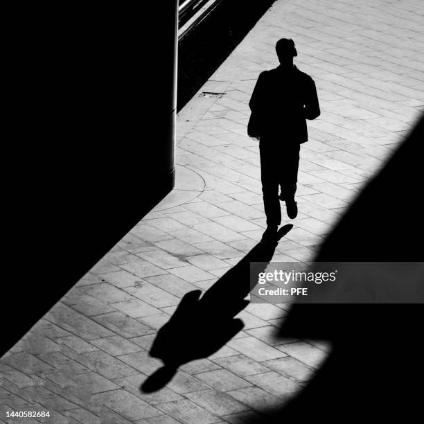 silhouette man in street in black and white - man walking silhouette stock pictures, royalty-free photos & images